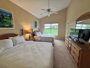 A bedroom with two beds, a ceiling fan, a TV, and a window with a view of the outdoors.