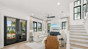 A spacious living room with a sofa, armchairs, a coffee table, a TV, and a staircase. - ☀️Infinity Pool-4BR-30A Cypress Stay (Santa Rosa Beach)