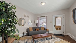 A living room with a sofa, coffee table, and a large plant.