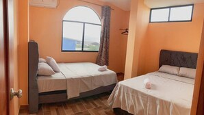 Ein Zimmer mit zwei Betten, einem großen Fenster mit Blick und einer Tür.
