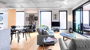 A modern living room with a dining area, a sofa, a coffee table, and a TV.