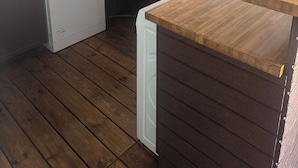 Una cocina con encimeras de madera, lavavajillas y una ventana con persianas.