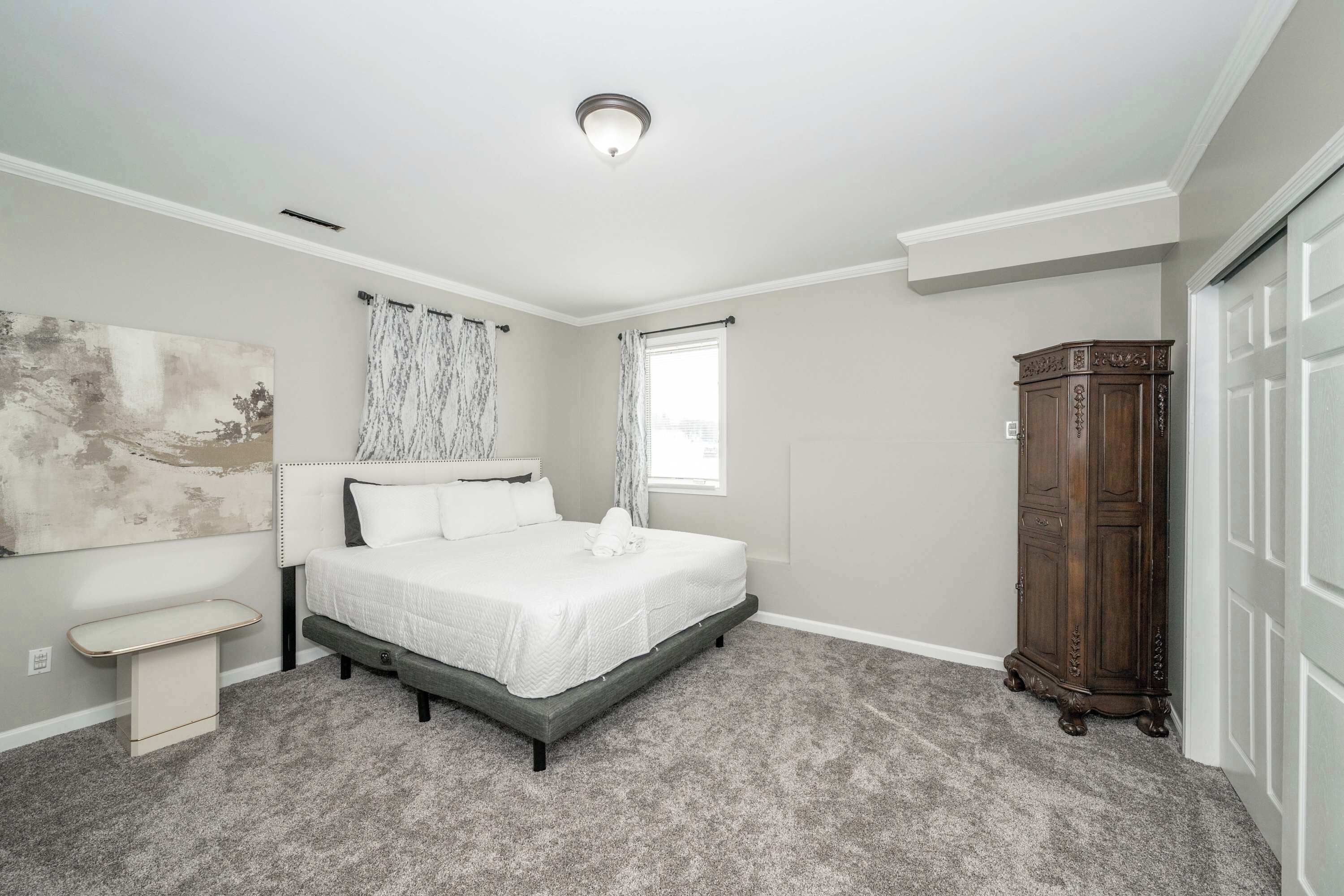 A bedroom with a bed, a nightstand, a wardrobe, and a window.