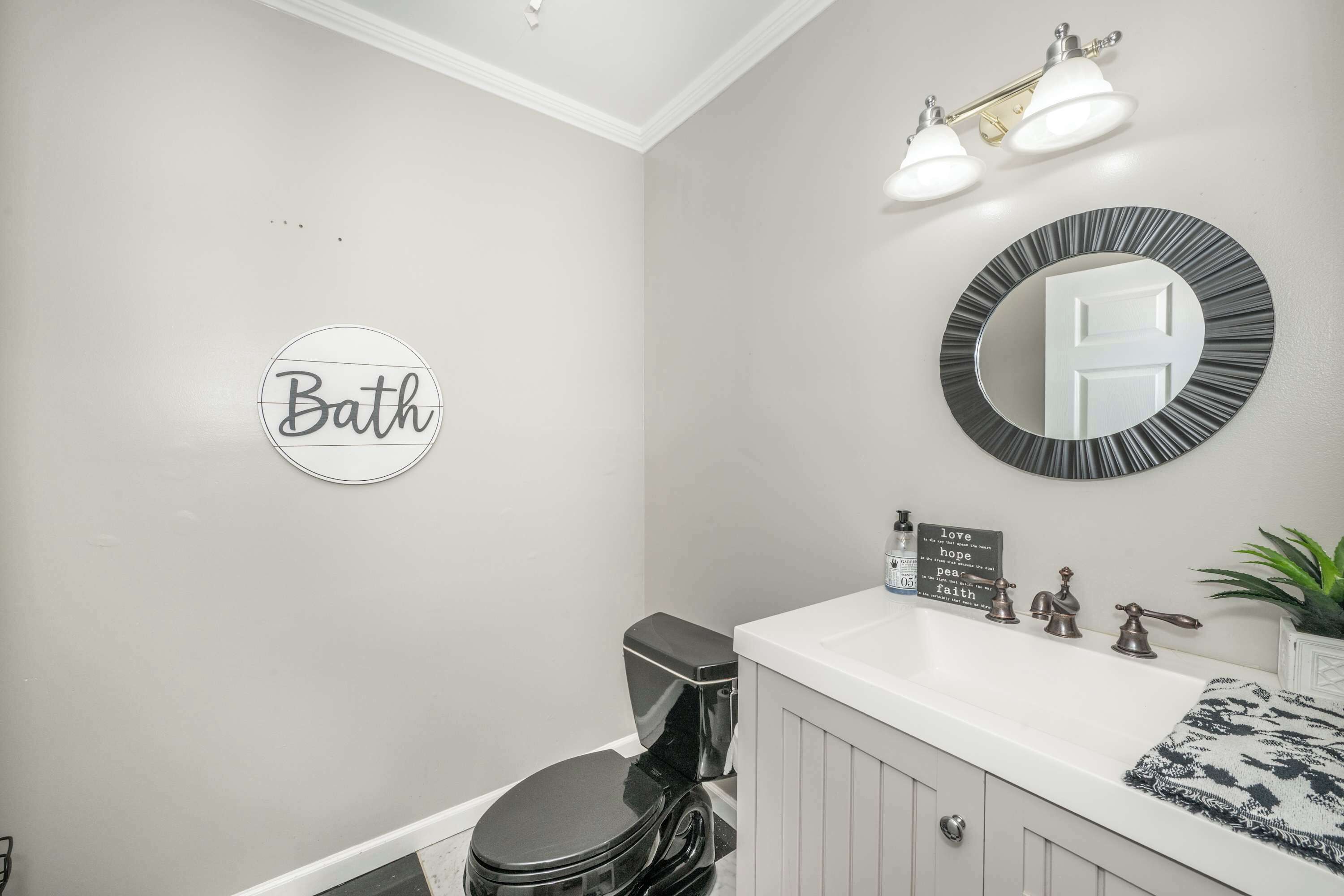 Un baño con inodoro, lavamanos y espejo. Hay un cartel en la pared que dice 'Bath'.