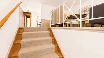 A staircase with carpeted steps leading to a landing with a white railing.