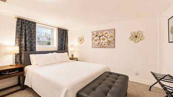 A bedroom with a bed, bedside tables, a bench, and wall art.