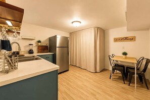 A compact kitchen with a refrigerator, sink, and dining area with chairs and a table. - The Gahanna Getaway (Columbus)