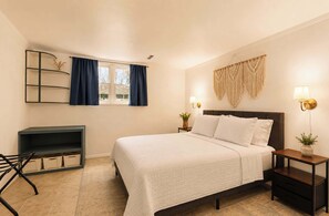 Quarto com cama, mesas de cabeceira, escrivaninha e uma cadeira.