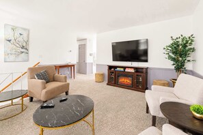 A living room with a fireplace, a television, and two sofas. - The Gahanna Getaway (Columbus)