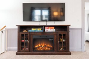 A fireplace with a TV mounted above it, surrounded by a mantel with game boxes. - The Gahanna Getaway (Columbus)