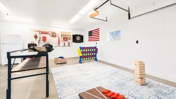 A modern, well-lit room with a ping pong table, a dartboard, and a jigsaw puzzle on the floor.