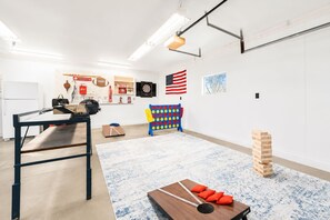 A modern, well-lit room with a ping pong table, a dartboard, and a jigsaw puzzle on the floor. - The Gahanna Getaway (Columbus)