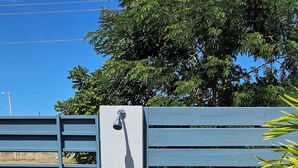 A gated entrance with a blue gate, a wall-mounted water spigot, and a small plant.