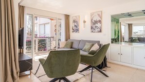 Un salon moderne avec un canapé gris, des fauteuils verts et un meuble blanc.