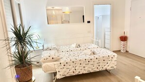 Een slaapkamer met een bed, nachtkastje, potplant en een spiegel.