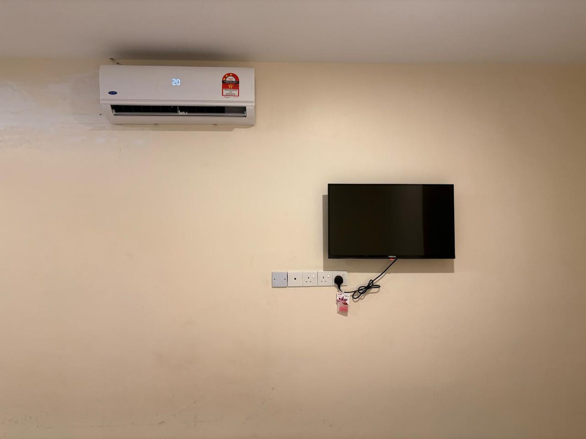 Un climatiseur fixé au mur et un téléviseur à écran plat, le tout installé sur un mur uni.