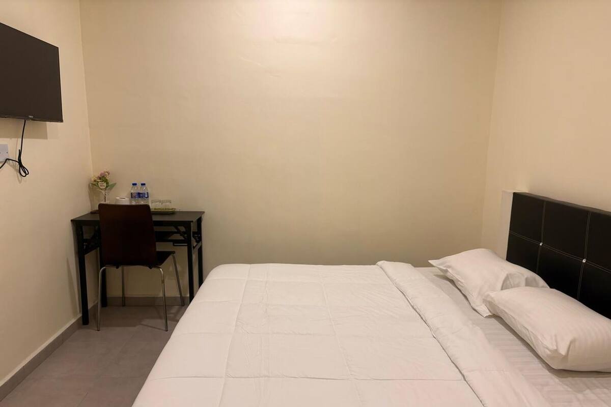 A hotel room with a bed, a desk, and a chair.