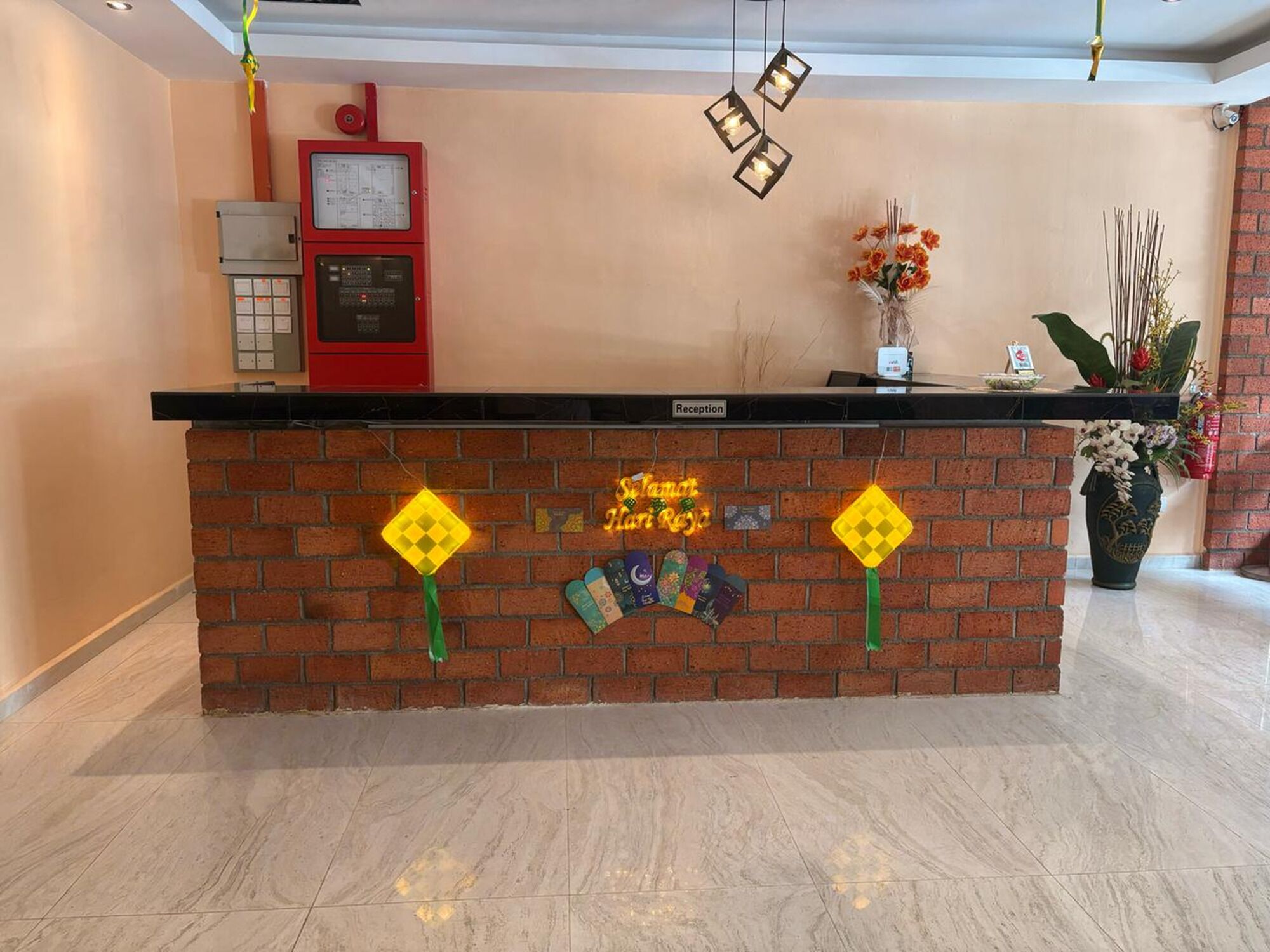 A reception desk with a brick base, a red control panel, and a sign indicating 'Reception'.