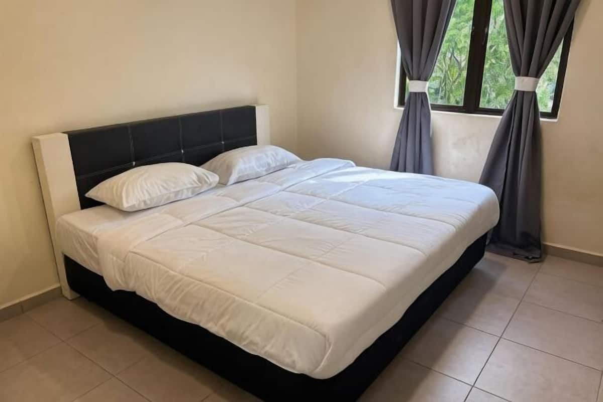 A bed with a black headboard, white bedding, and a window with curtains.