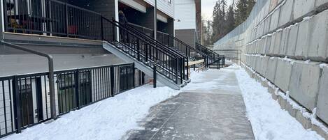 Un sendero cubierto de nieve que conduce a un edificio con escaleras y barandilla.