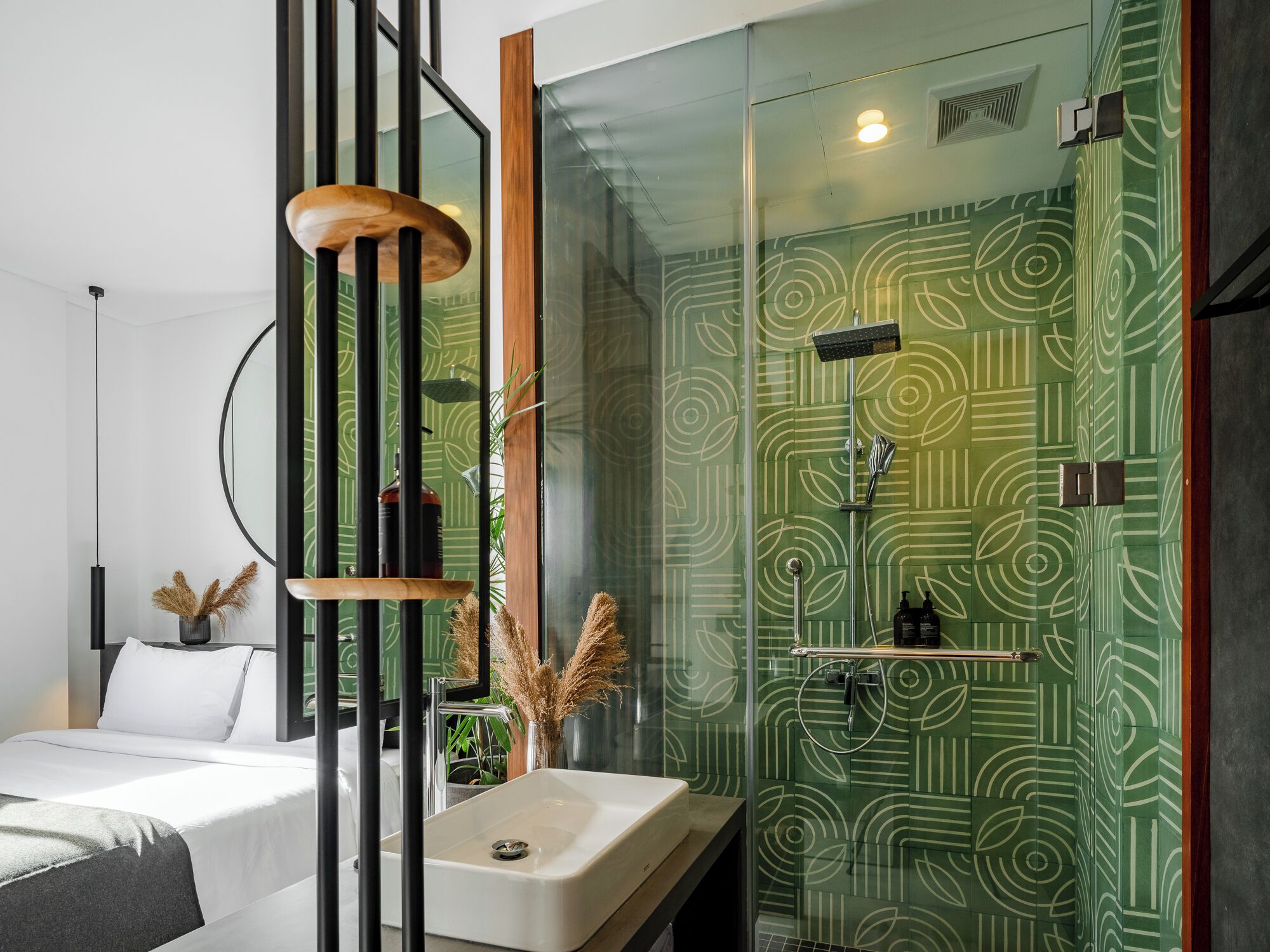 Et moderne badeværelse med væg i grønt mønster, en hvid vask og en brusekabine i glas.