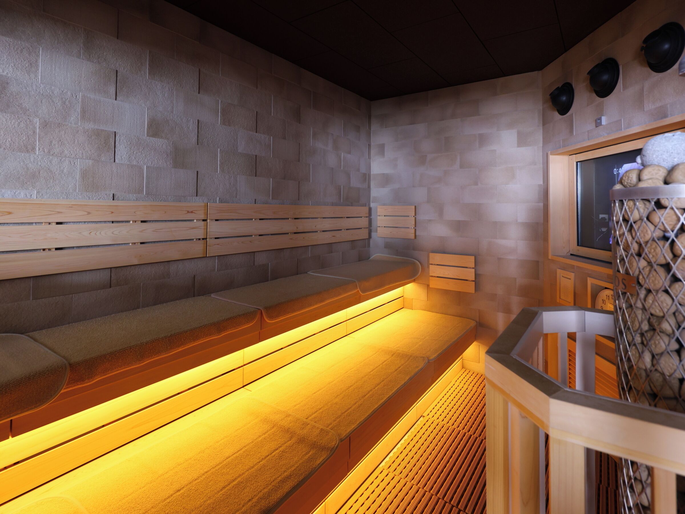 A sauna with wooden benches and a tiled wall.