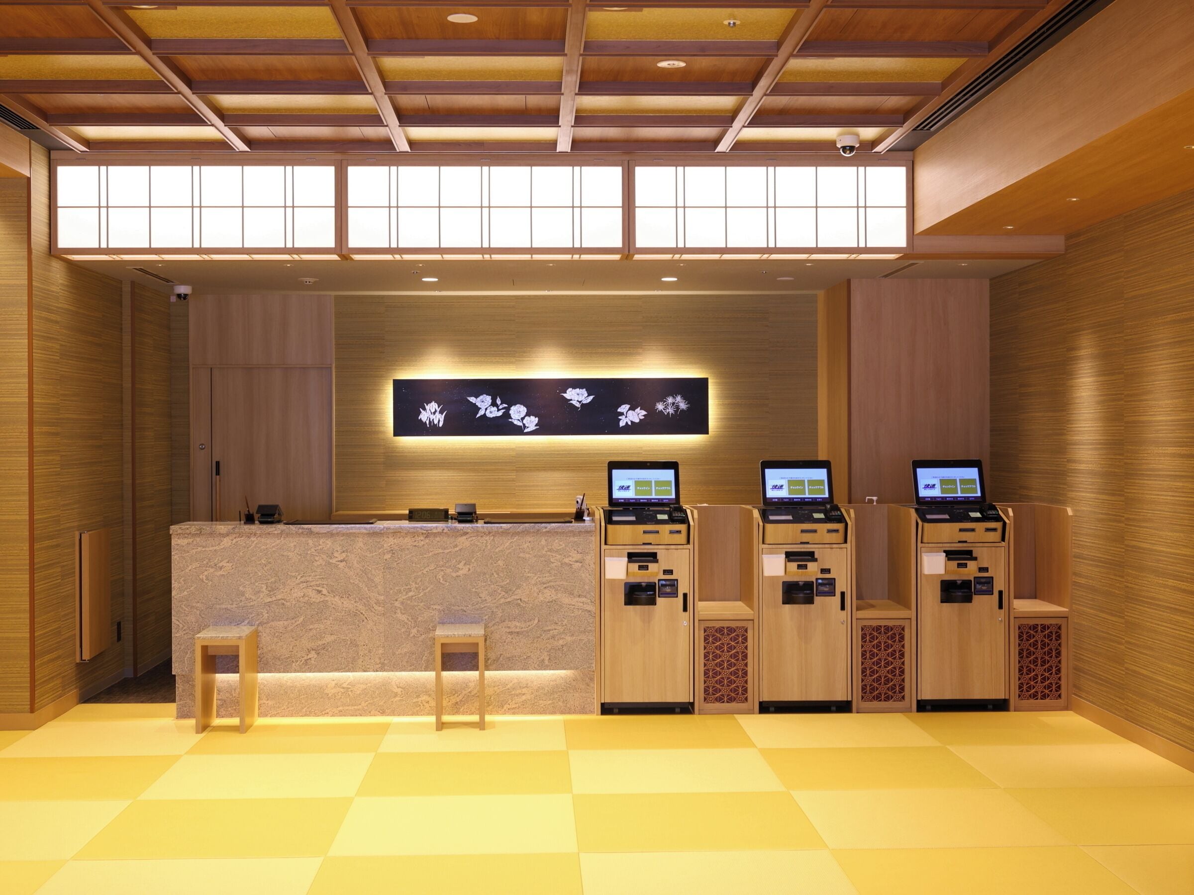 A reception area with a wooden reception desk, two computer kiosks, and a wall-mounted display.