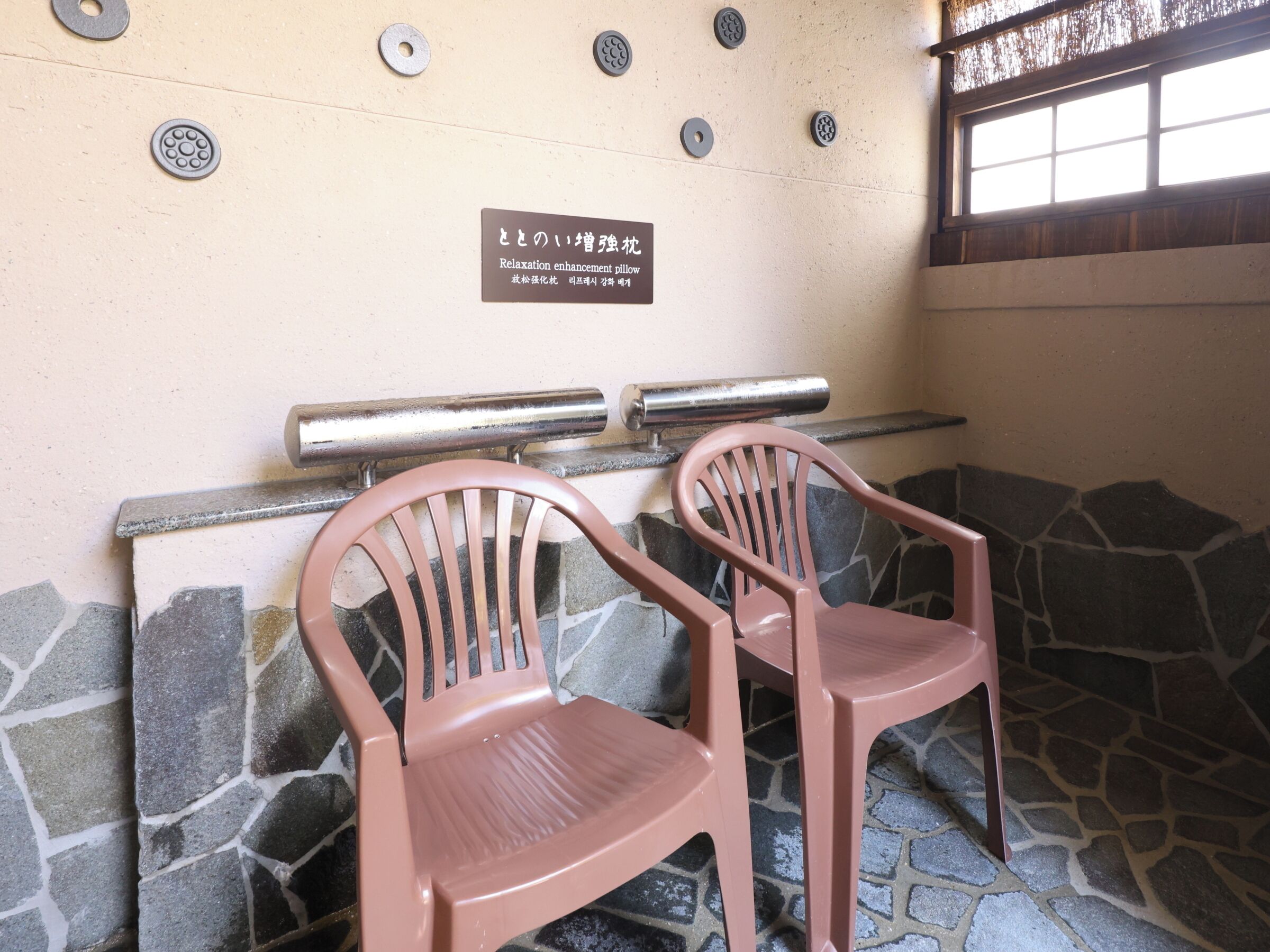 Two plastic chairs with a stone wall and a metal railing in the background.