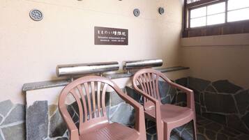 Two plastic chairs with a stone wall and a metal railing in the background.