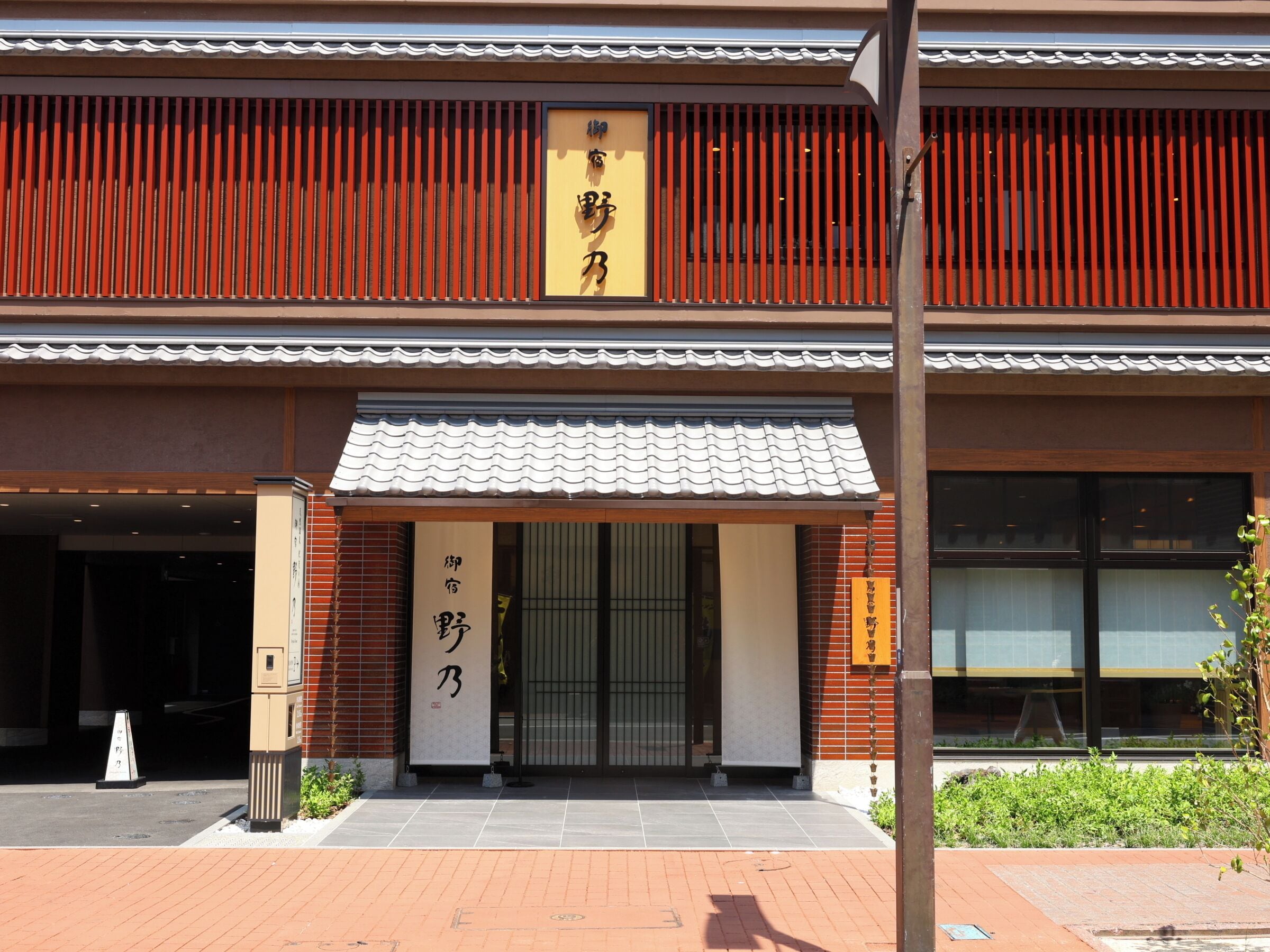 A building with a traditional tiled roof, a signboard with Chinese characters, and a brick facade.
