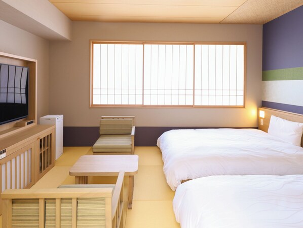 Una habitación de hotel con una cama, un sofá, un televisor y una ventana.