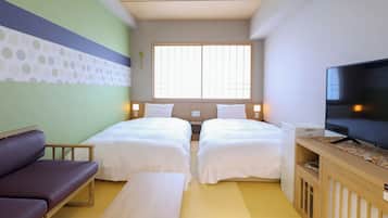 A hotel room with two beds, a sofa, a TV, and a window with natural light.