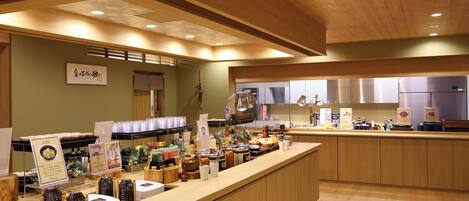 Un restaurante moderno con paneles de madera, una barra central con exhibición de alimentos y una distribución limpia y organizada.