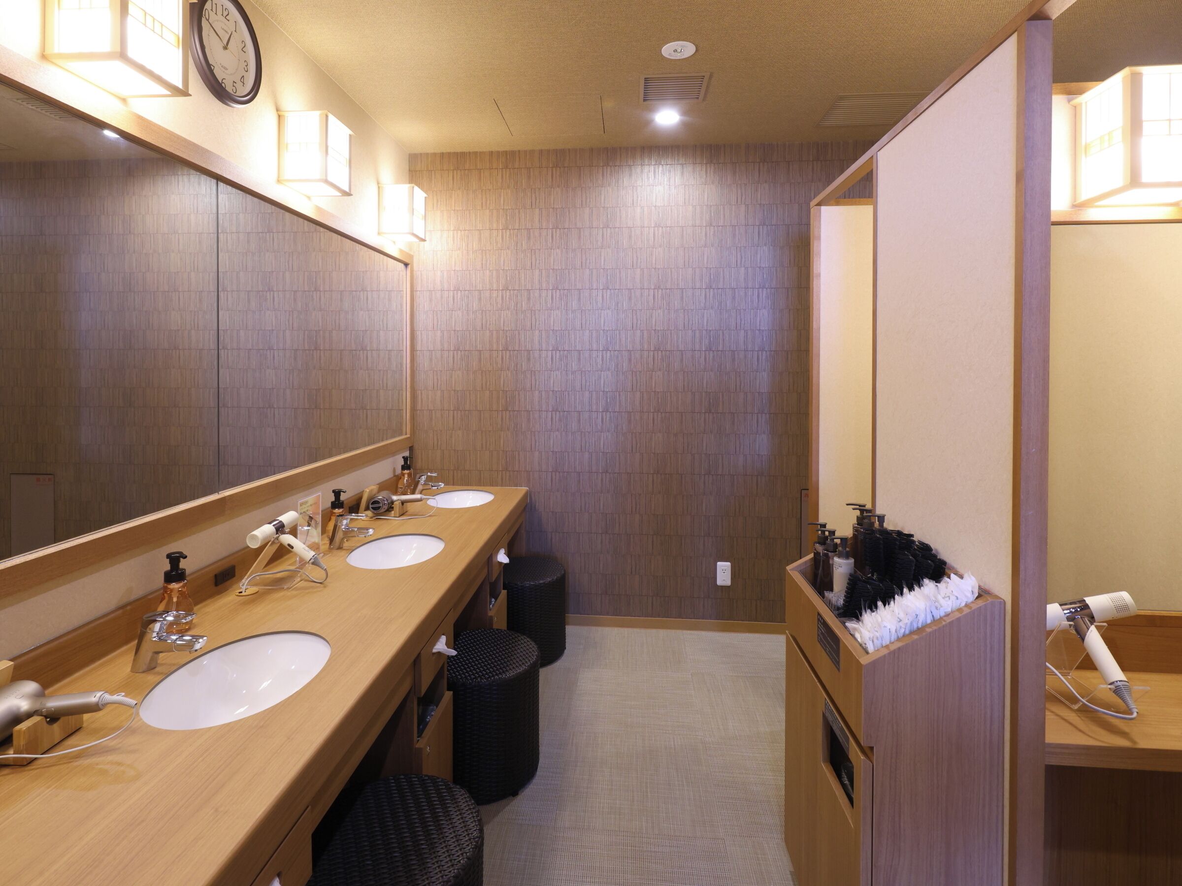 A modern bathroom with two sinks, a large mirror, and a hairdryer on a stand.