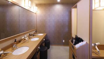 A modern bathroom with two sinks, a large mirror, and a hairdryer on a stand.