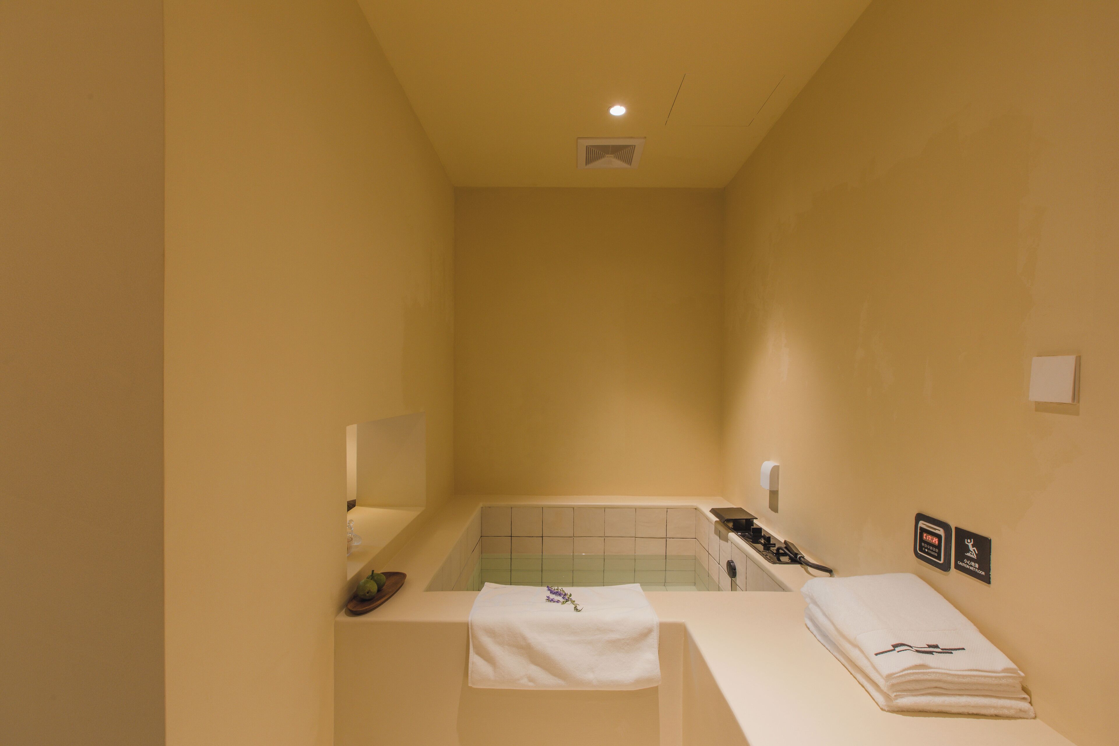 Une petite salle de bain composée d’une seule pièce, avec une baignoire, un lavabo et un miroir. On y trouve des serviettes et des articles de toilette sur le comptoir.