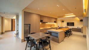 Una cocina moderna con una isla central, electrodomésticos integrados y un comedor con sillas.