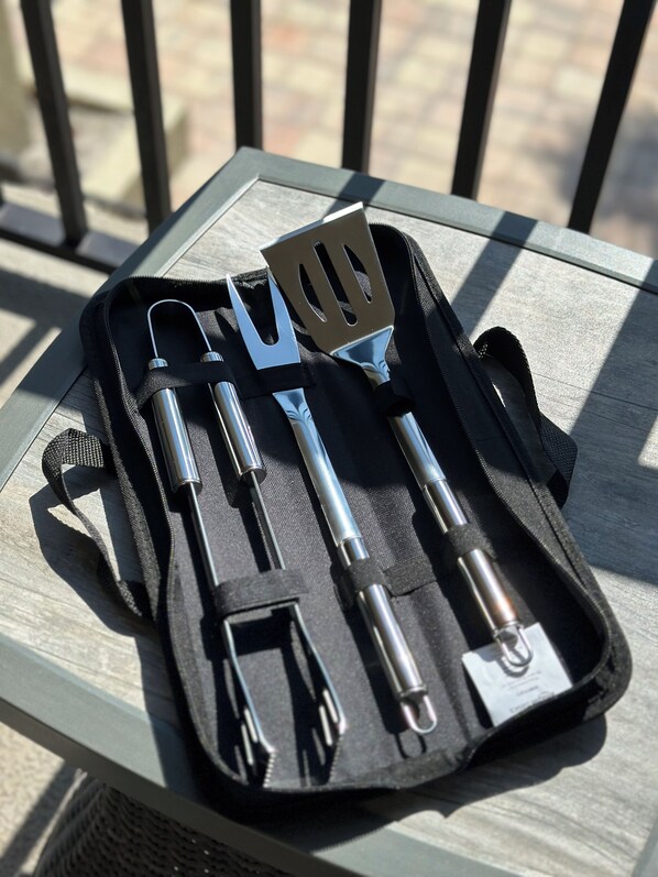 Une boîte à outils noire contenant des ustensiles en métal, posée sur une table en bois.