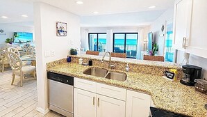 Een moderne keuken met een granieten aanrechtblad, een RVS spoelbak en witte kasten.