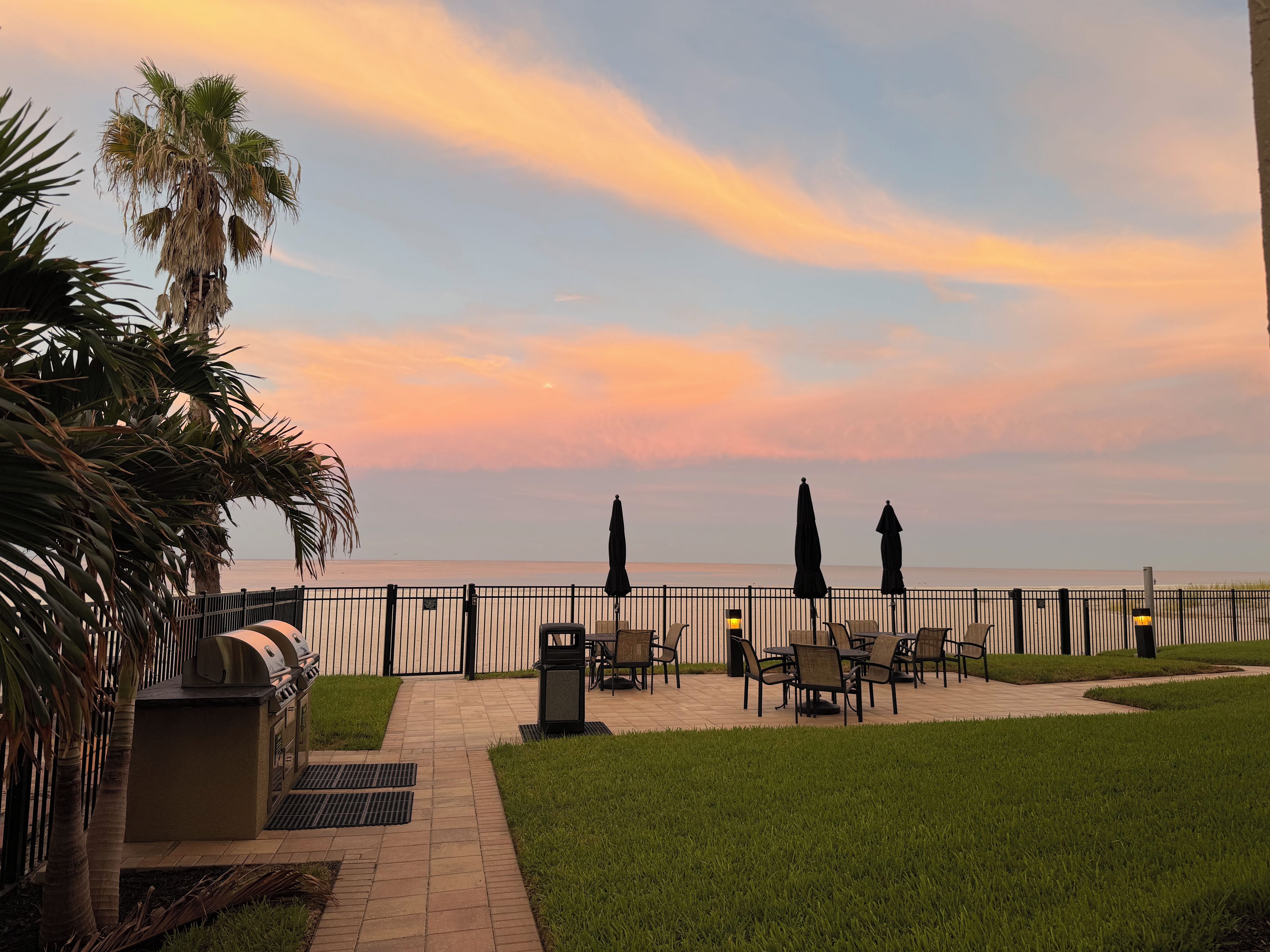 A patio area with outdoor seating, a grill, and a view of the sea.