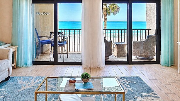 Een kamer met een glazen deur die uitkomt op een balkon met uitzicht op zee.