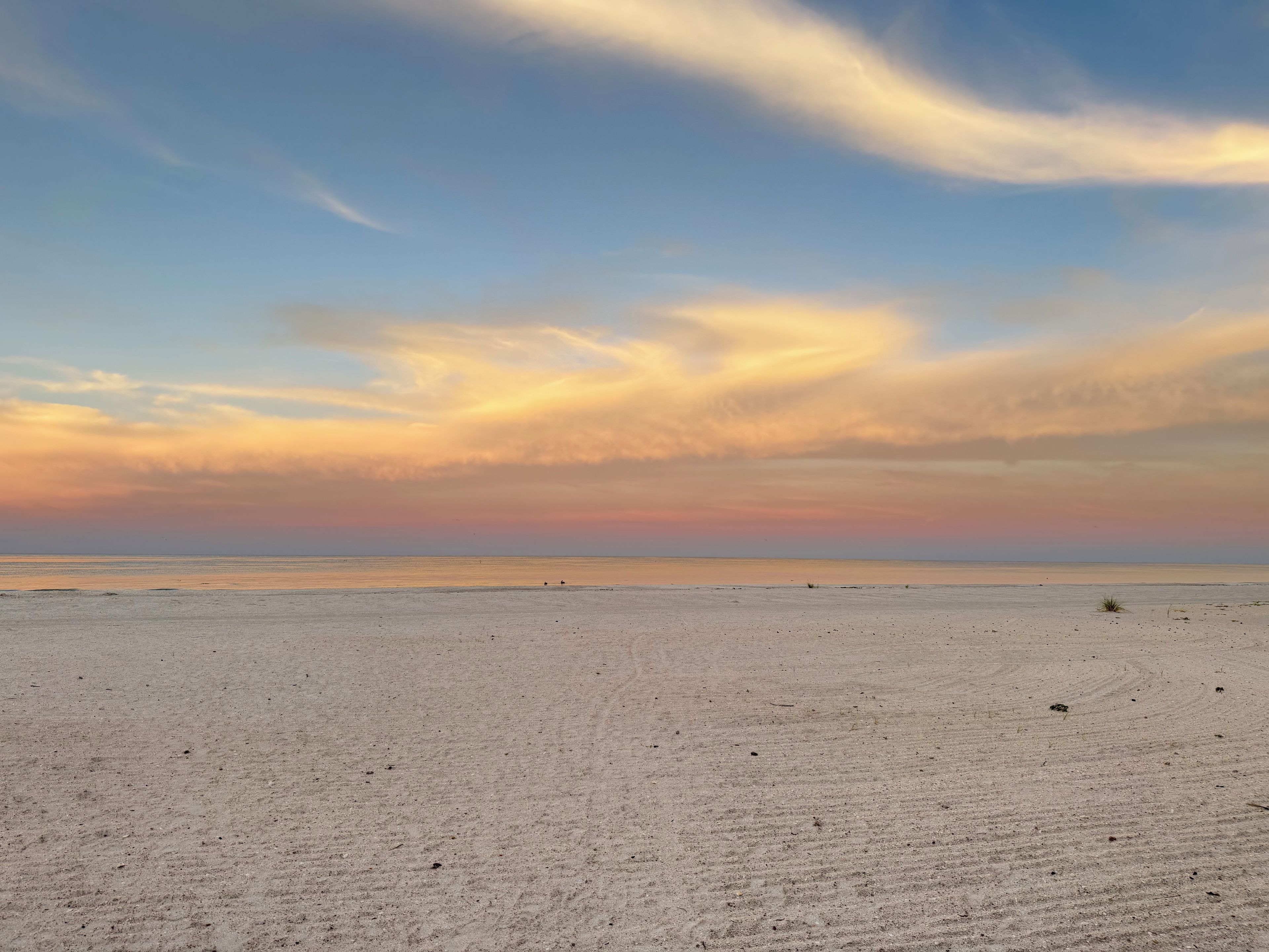 A beach with a wide sandy expanse and a distant horizon.