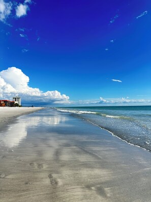 Una playa con cielo despejado, orilla arenosa y un edificio de techo rojo.