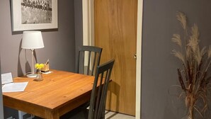 A dining area with a wooden table, chairs, a framed photograph on the wall, a lamp, and a vase with dried plants. - Le Havre Gris, a spacious private room for relaxing or working (Sherbrooke)
