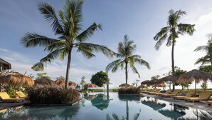 A pool area with lounge chairs and palm trees. - Seven Dreams A Pramana Experience (Penida Island)