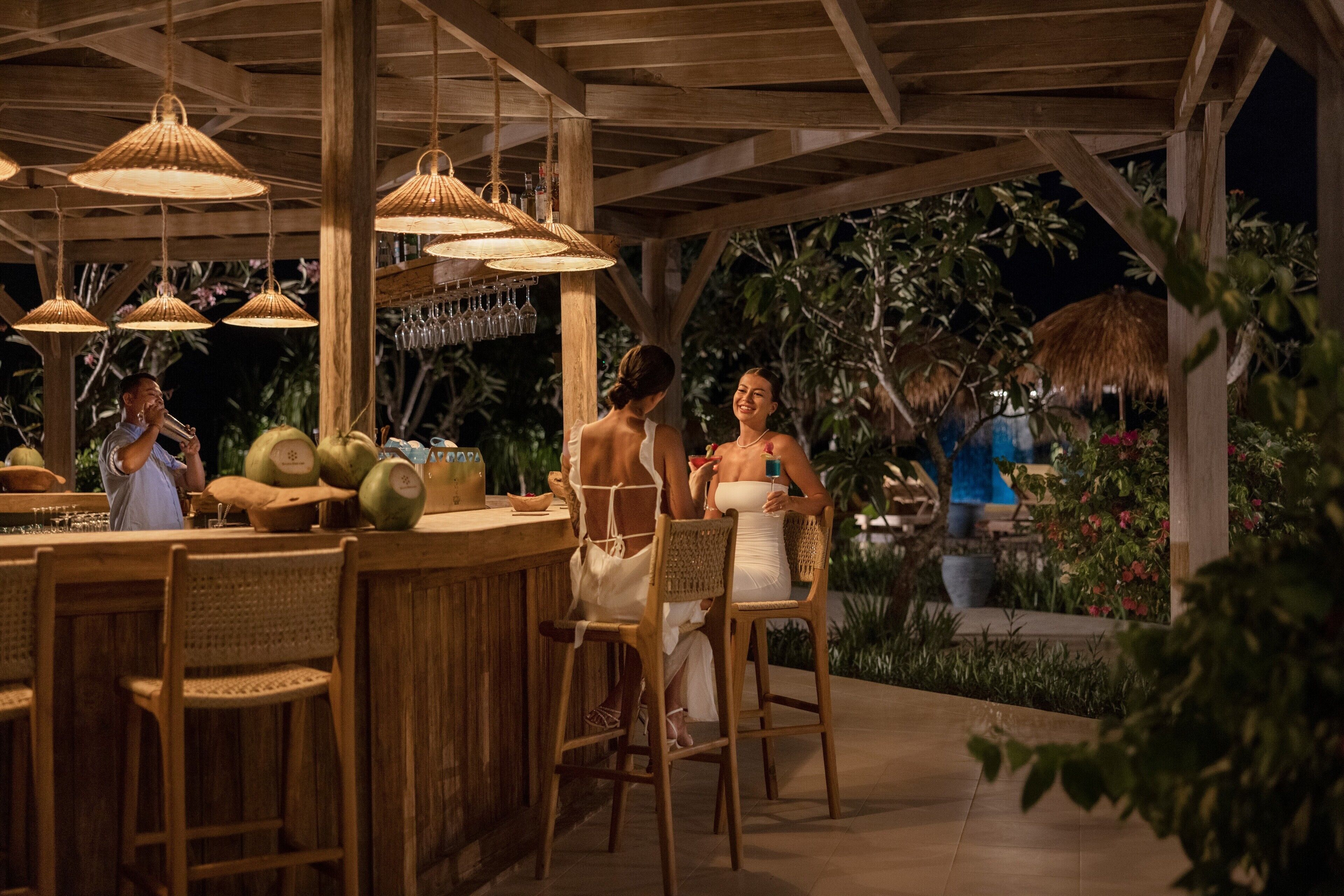 An outdoor bar area with wooden furniture and hanging lamps.