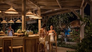 An outdoor bar area with wooden furniture and hanging lamps.