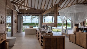 A spacious bathroom with a large bathtub, wooden vanity, and a view of the ocean. - Seven Dreams A Pramana Experience (Penida Island)