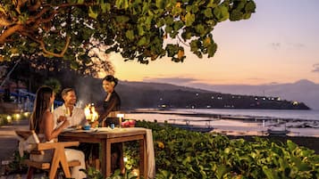 A dining table set outdoors with a view of the sea and mountains in the background.