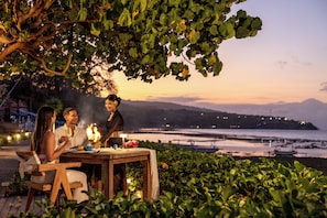 Una mesa de comedor al aire libre con vistas al mar y montañas en el fondo.